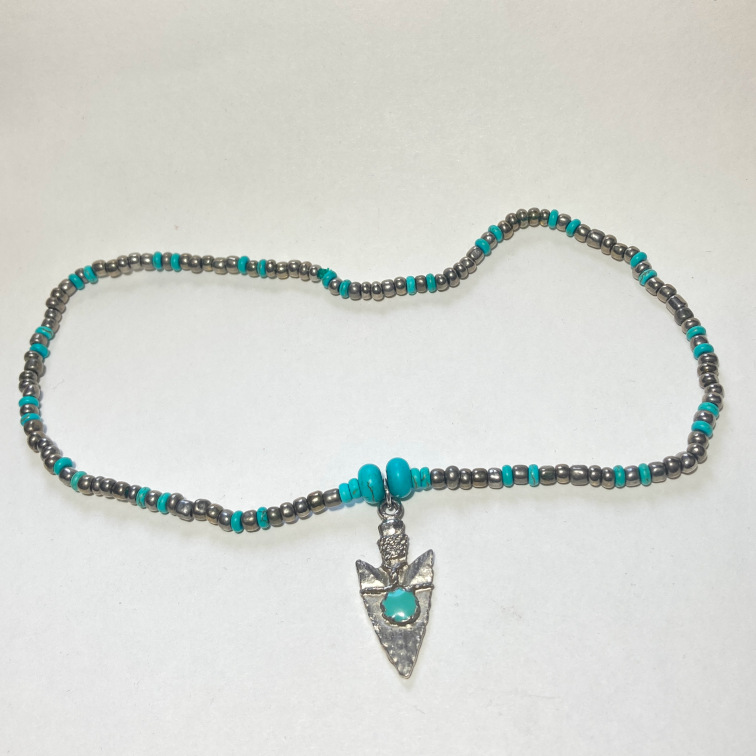 Metal arrowhead-style pendant with simple beads and turquoise accents